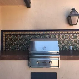 Outdoor kitchen with a blue and gold Spanish tile backsplash behind a built-in grill