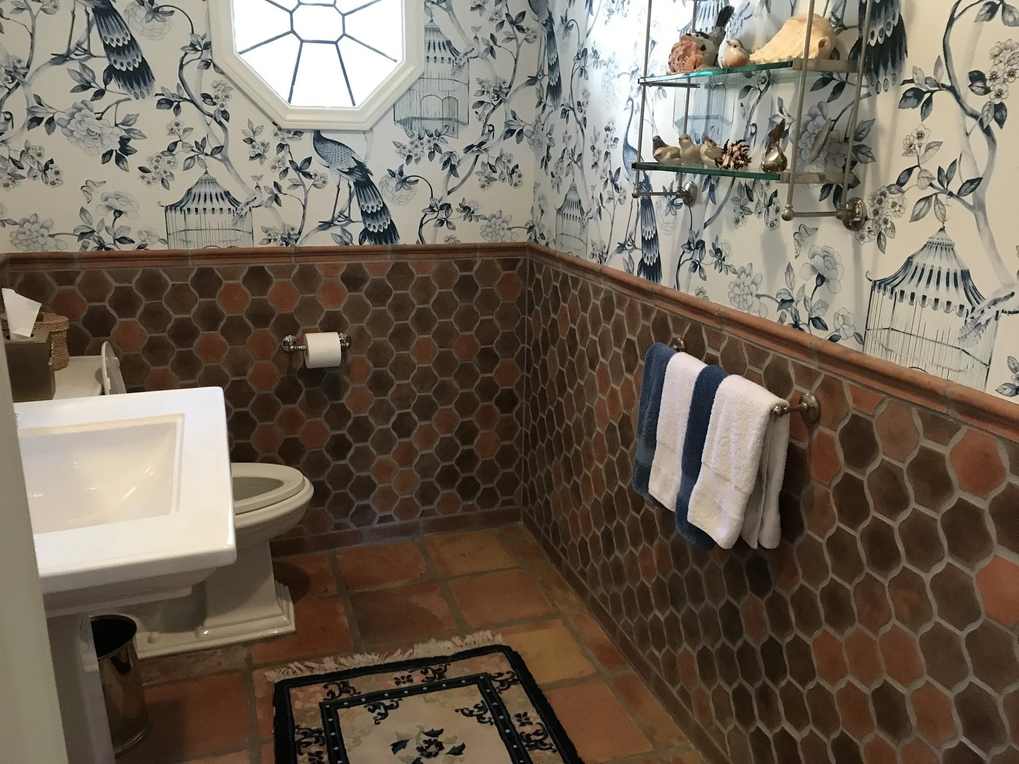 Powder room with a brown hexagon tile wainscot below blue and white chinoiserie wallpaper