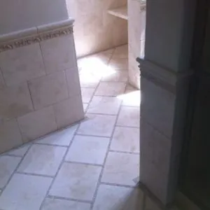Bathroom with diagonal limestone floor tile and a wall tile band with a decorative border