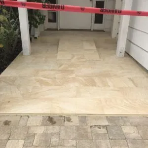 New travertine entry tile at a front door, meeting a paver walkway
