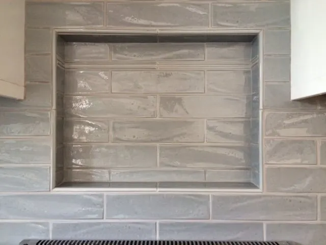 Recessed shower niche framed in gray glazed subway tile