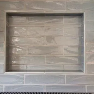 Recessed shower niche framed in gray glazed subway tile