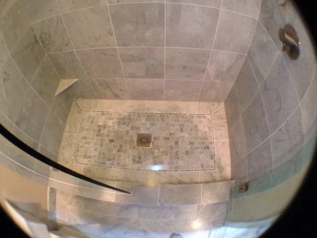 Walk-in shower with gray marble wall tile and a mosaic floor