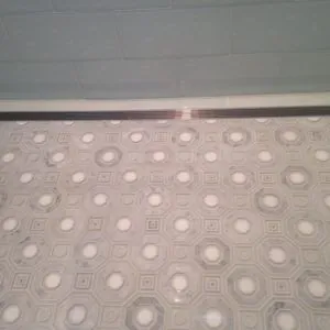 White and gray marble octagon-and-dot mosaic floor with a linear drain