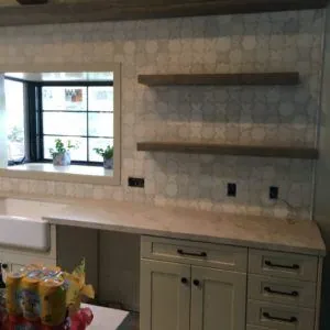 Kitchen wall of pale gray octagon tile with floating wood shelves