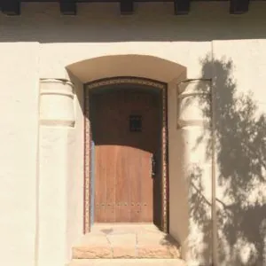 Spanish-style front entry with tiled steps and a decorative tile border around an arched wood door
