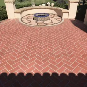 Red brick herringbone patio around a fire pit with a circular stone surround
