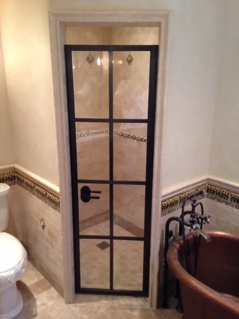 Bathroom with a steel-framed glass shower door, marble tile and a copper soaking tub