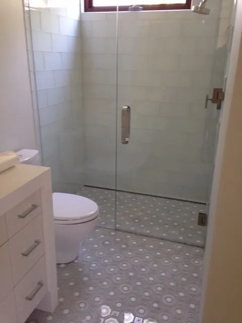 Bathroom with a frameless glass shower and a white and gray patterned mosaic floor