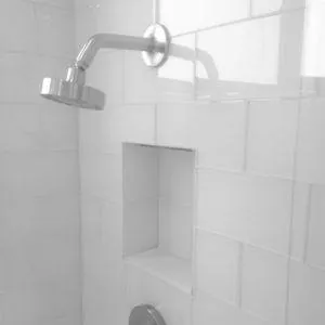 White subway tile shower with a recessed niche and a chrome shower head