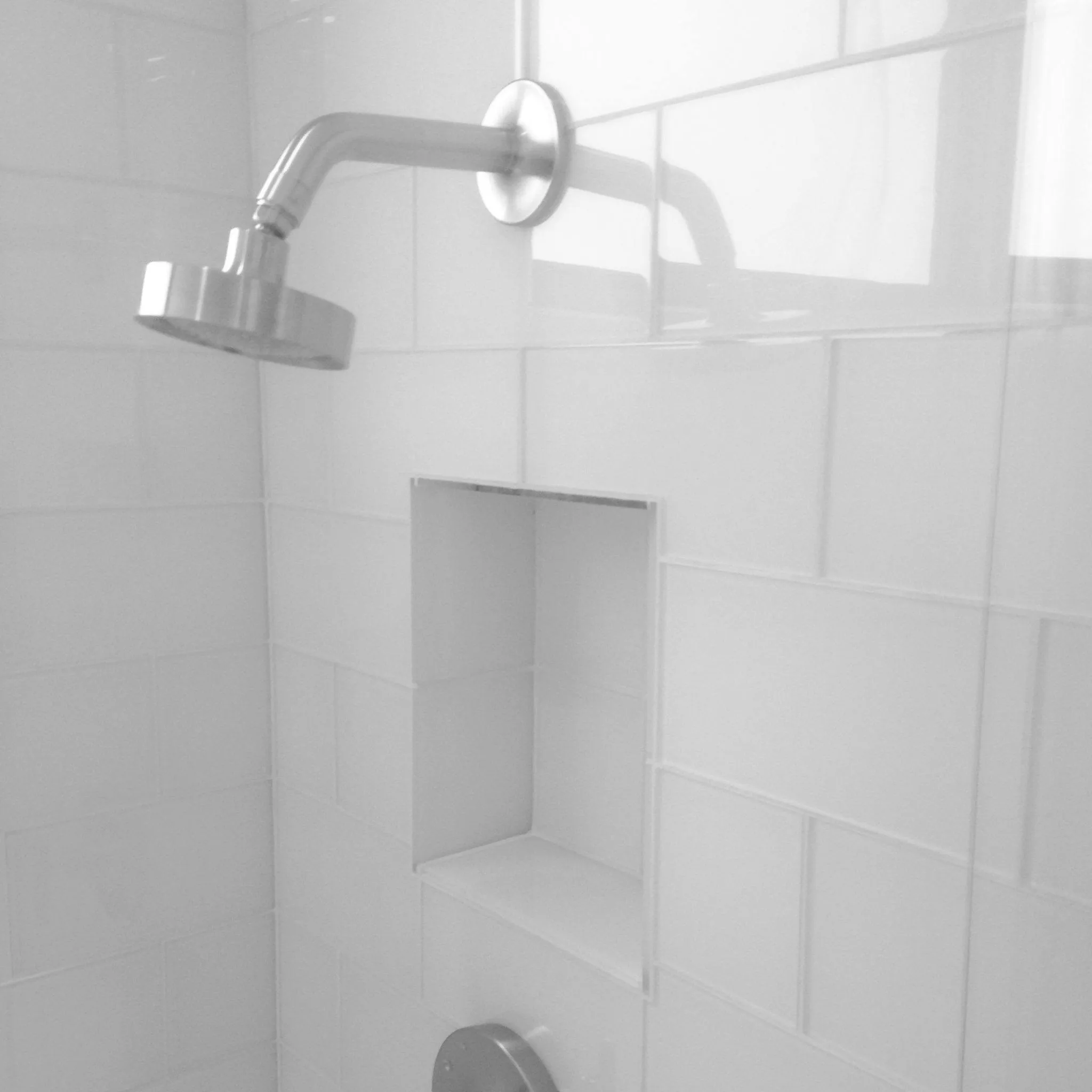 White subway tile shower with a recessed niche and a chrome shower head