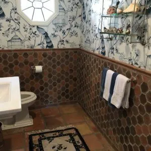 Powder room with a brown hexagon tile wainscot below blue and white chinoiserie wallpaper