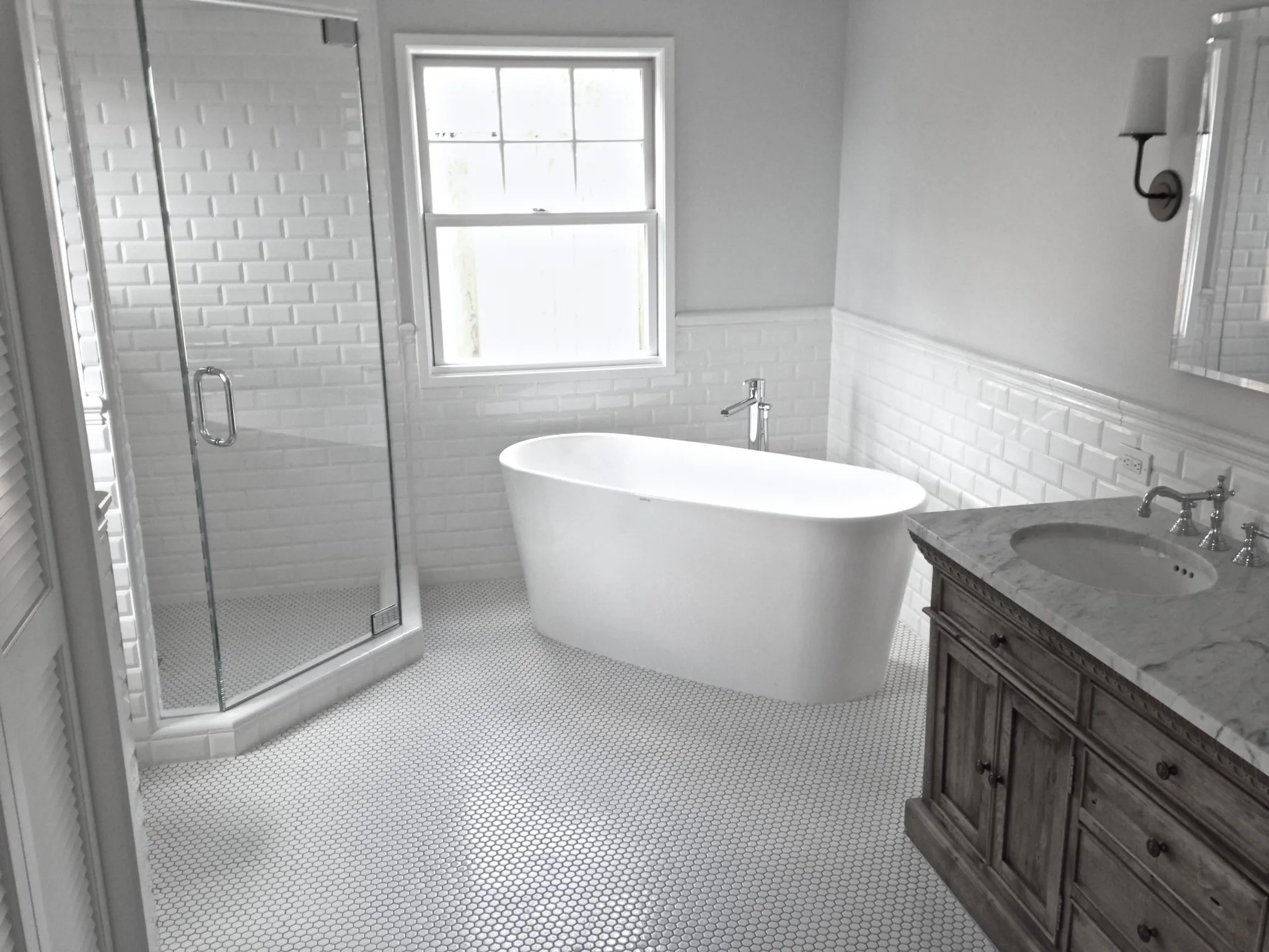Bathroom with a white subway tile wainscot, freestanding tub and white penny-tile floor