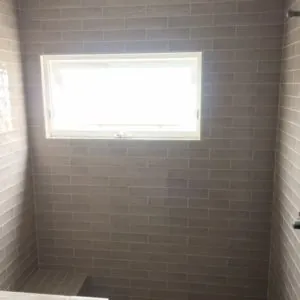 Shower walls in gray glazed subway tile around a window
