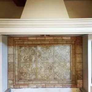 Carved-relief tile panel with a stone border beneath a plaster range hood
