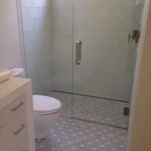Bathroom with a frameless glass shower and a white and gray patterned mosaic floor
