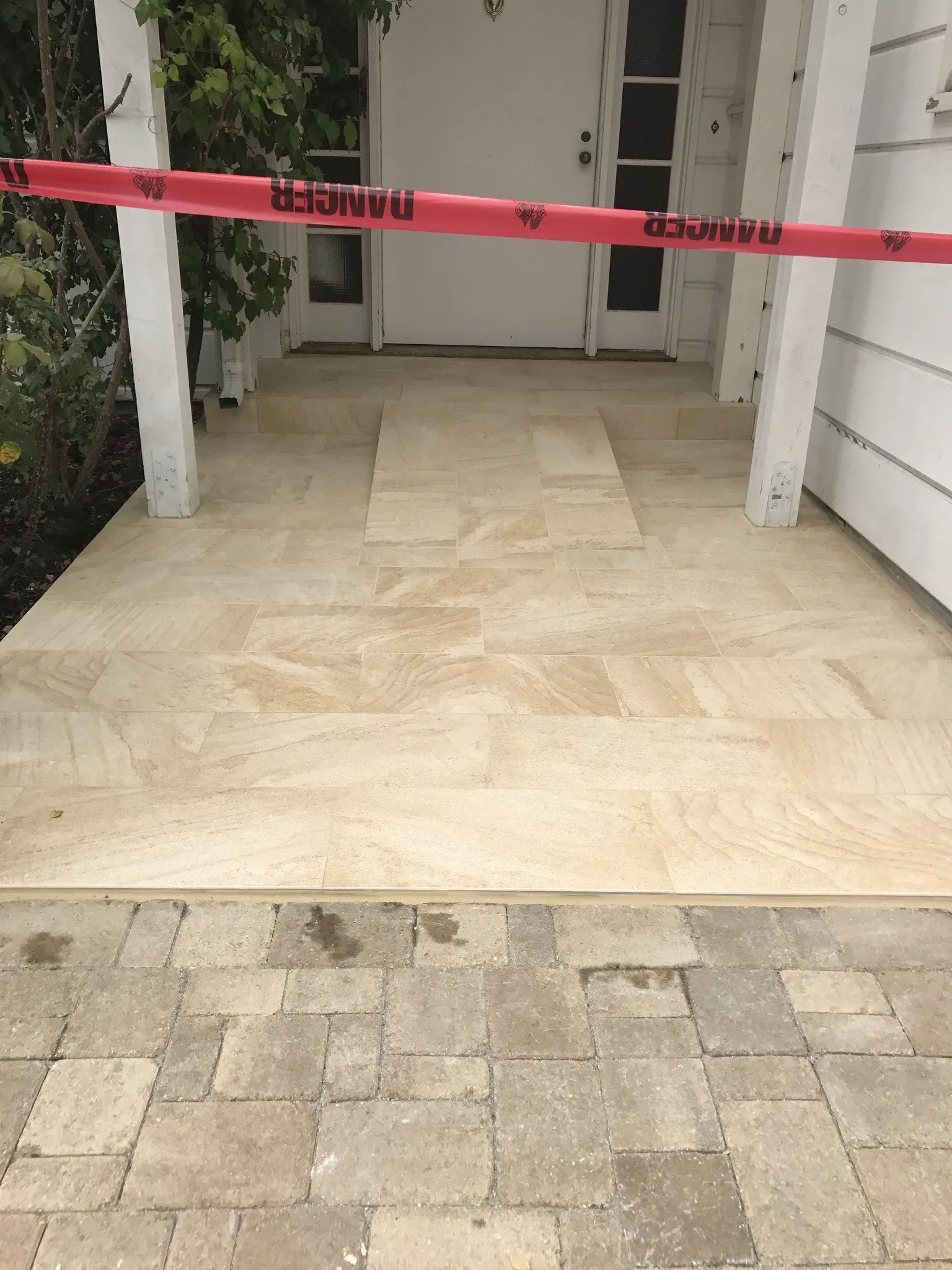 New travertine entry tile at a front door, meeting a paver walkway