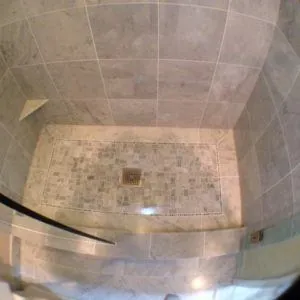Walk-in shower with gray marble wall tile and a mosaic floor