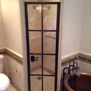 Bathroom with a steel-framed glass shower door, marble tile and a copper soaking tub