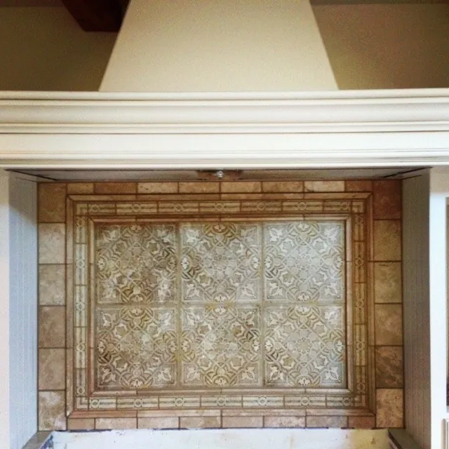 Carved-relief tile panel with a stone border beneath a plaster range hood