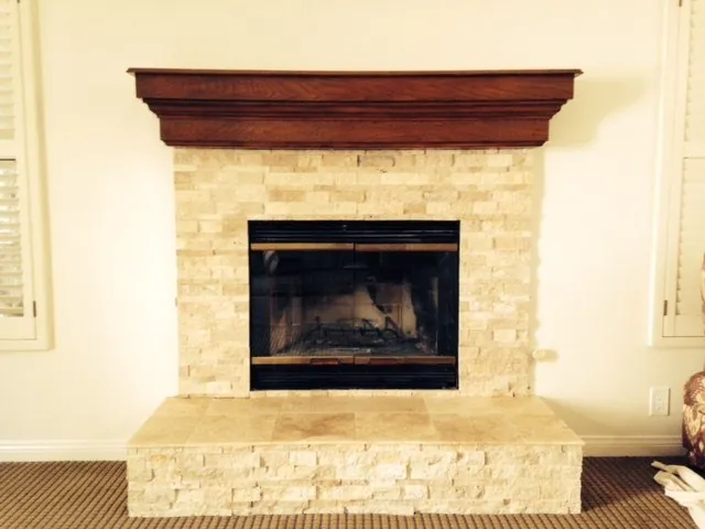 Fireplace with a stacked travertine surround and hearth below a wood mantel