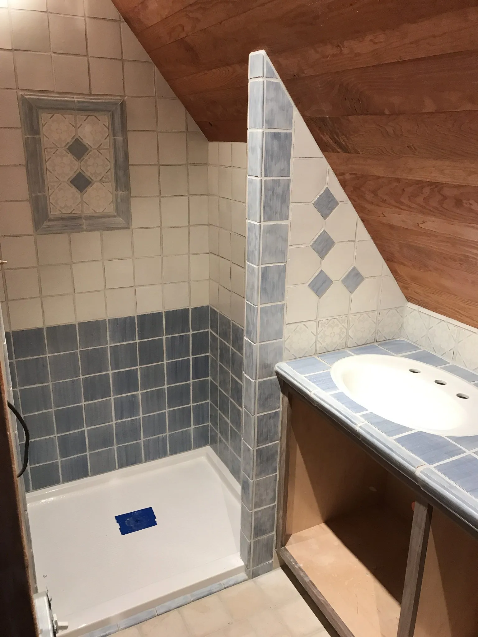 Bathroom remodel in progress with blue and white tile, diamond inlays and a tiled vanity