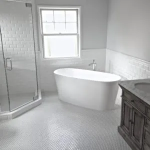 Bathroom with a white subway tile wainscot, freestanding tub and white penny-tile floor