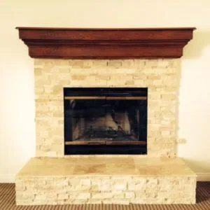 Fireplace with a stacked travertine surround and hearth below a wood mantel